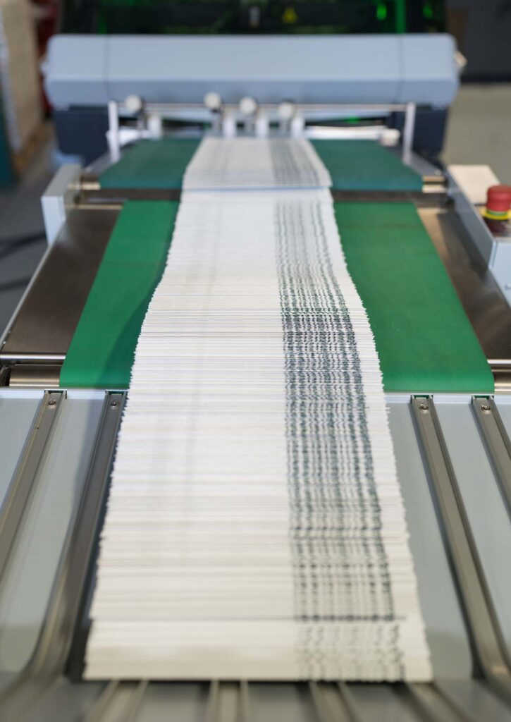 Our press machine completes finished saddle stitched booklets on our conveyor belt.