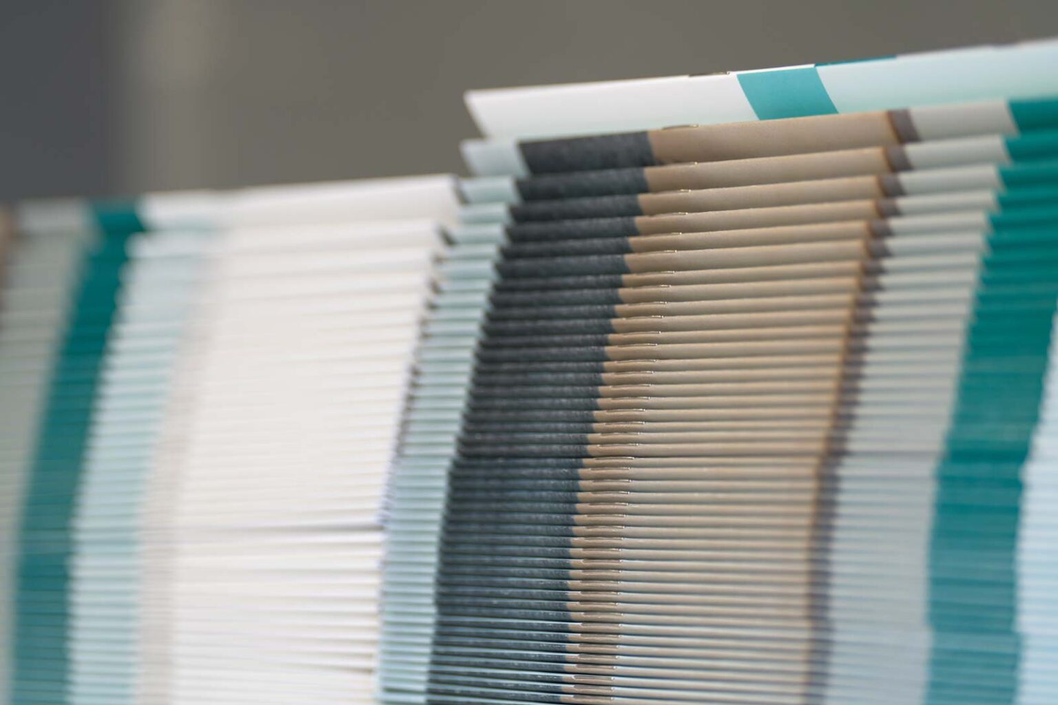 A stack of finished, colorful, saddle stitched bound booklets ready to ship to our customer.